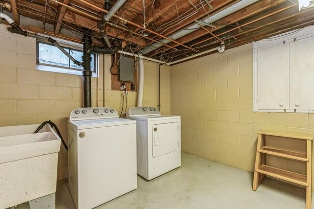 clothes washing area with electric panel, washer and dryer, and a sink