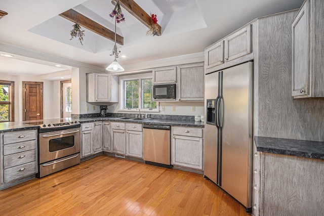 kitchen with beam ceiling, appliances with stainless steel finishes, a tray ceiling, light hardwood / wood-style flooring, and sink