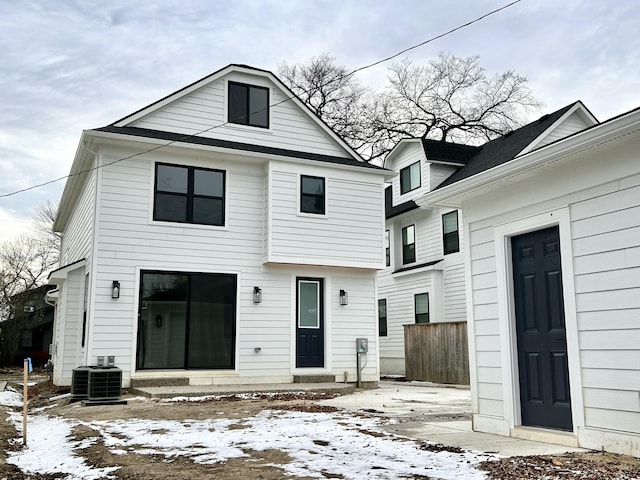 snow covered rear of property featuring central AC