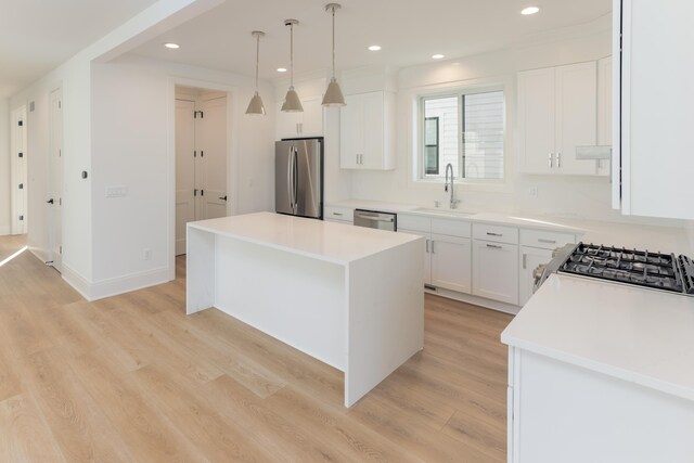 kitchen with pendant lighting, a center island, sink, appliances with stainless steel finishes, and white cabinetry