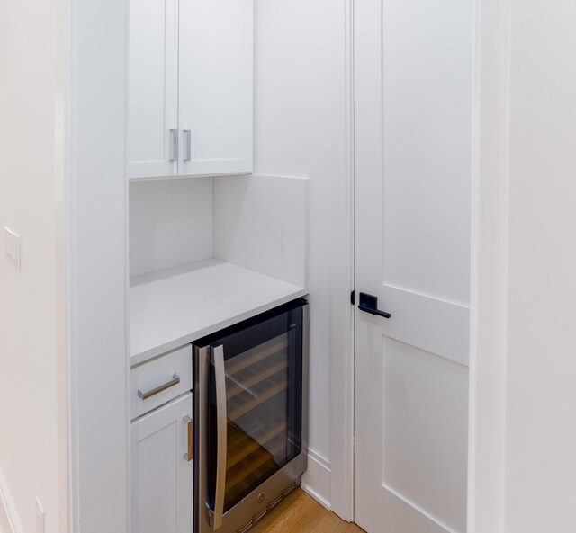 bar with white cabinets, wine cooler, and light hardwood / wood-style flooring