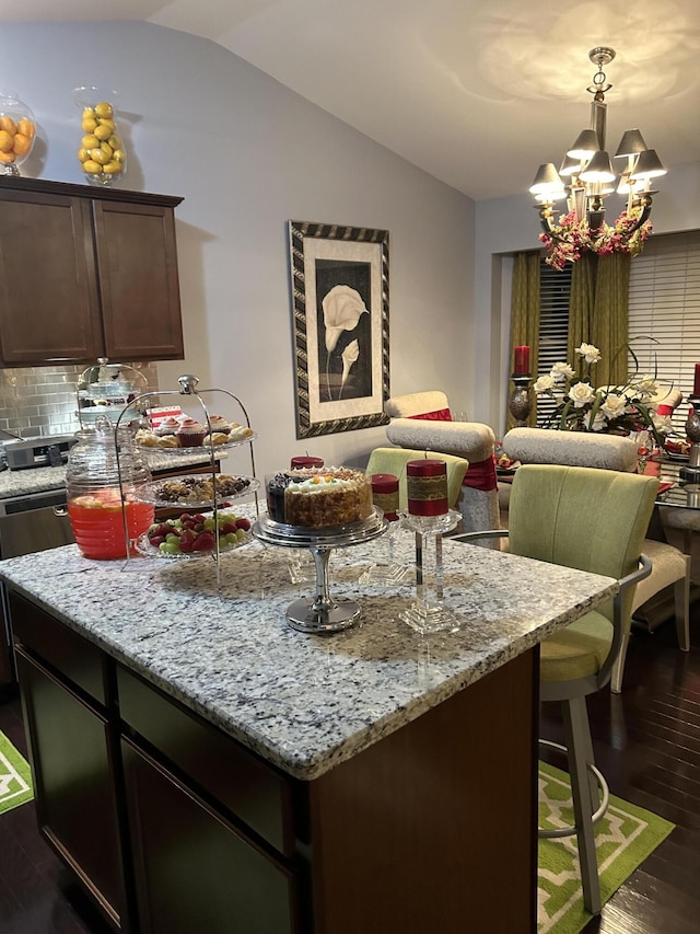 kitchen with tasteful backsplash, light stone counters, dark brown cabinetry, a notable chandelier, and dark hardwood / wood-style floors