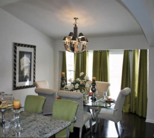 dining area featuring a notable chandelier, dark hardwood / wood-style flooring, and vaulted ceiling