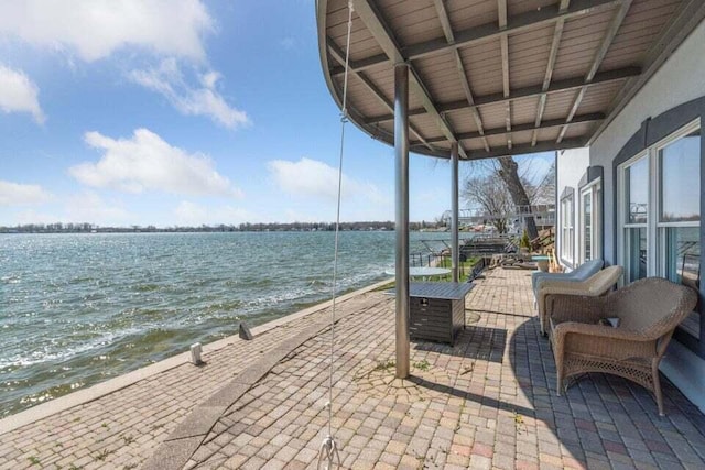 view of patio with a water view and a beach view