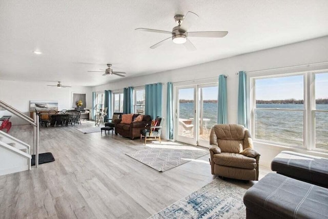 living room featuring light hardwood / wood-style flooring, a textured ceiling, and a water view