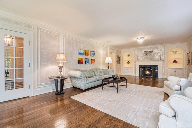 living room with ornamental molding, wood-type flooring, and built in shelves