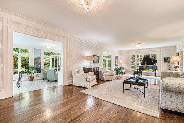 living room featuring an inviting chandelier, ornamental molding, and wood-type flooring