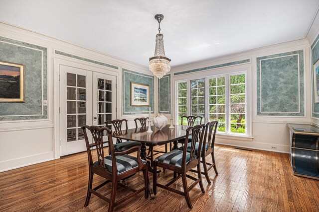 dining space featuring french doors, crown molding, a notable chandelier, and wood-type flooring