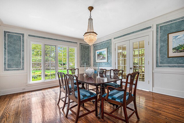 dining space with french doors, hardwood / wood-style flooring, ornamental molding, and an inviting chandelier