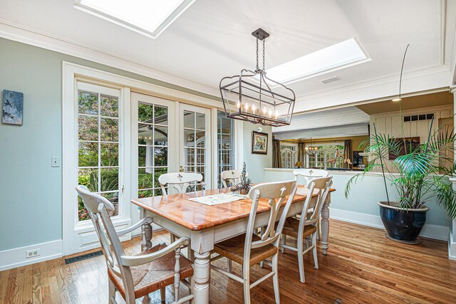 dining room with ornamental molding, a notable chandelier, and hardwood / wood-style floors