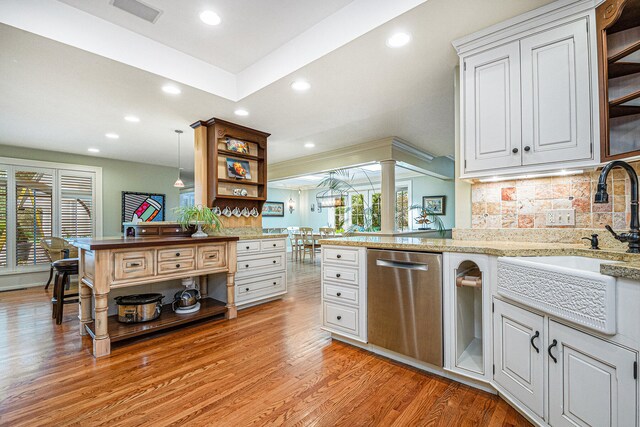 kitchen with tasteful backsplash, light hardwood / wood-style floors, decorative light fixtures, stainless steel dishwasher, and white cabinets