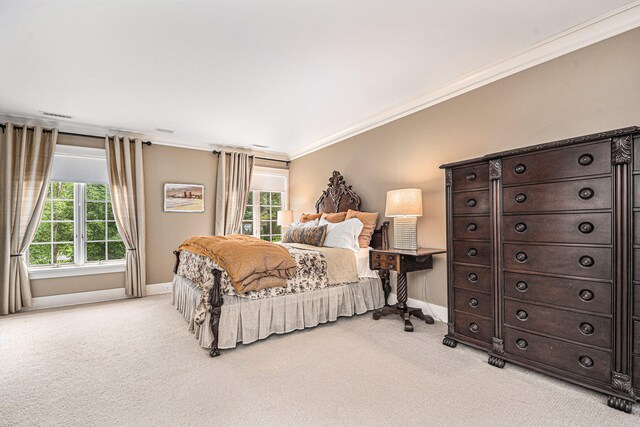 bedroom with ornamental molding and light colored carpet