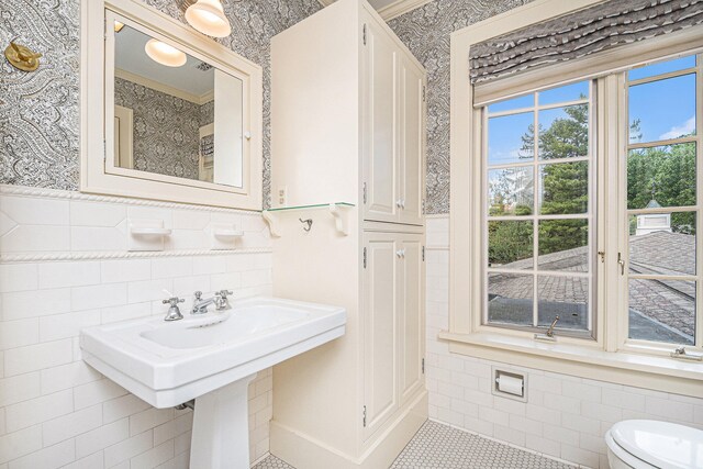 bathroom with toilet, ornamental molding, and tile walls