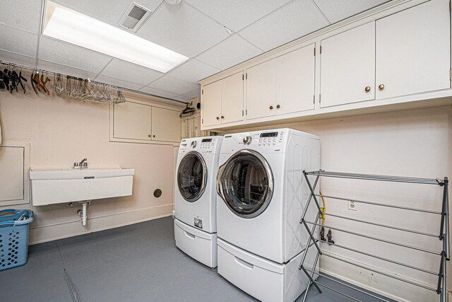 washroom with sink, independent washer and dryer, and cabinets