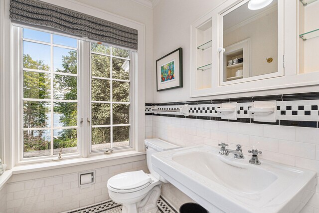 bathroom with toilet, a healthy amount of sunlight, tile walls, and sink