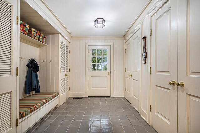 mudroom with crown molding and wooden walls