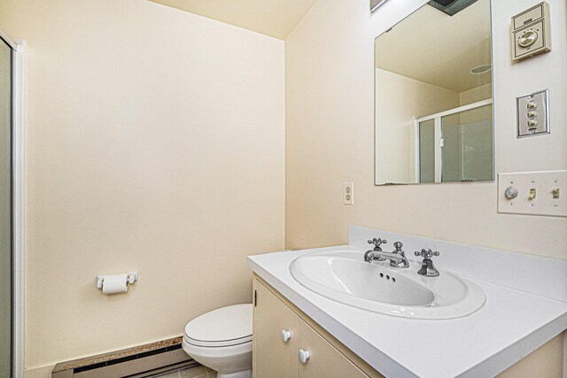 bathroom featuring baseboard heating, vanity, toilet, and walk in shower