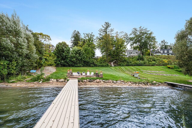 view of dock with a water view and a lawn