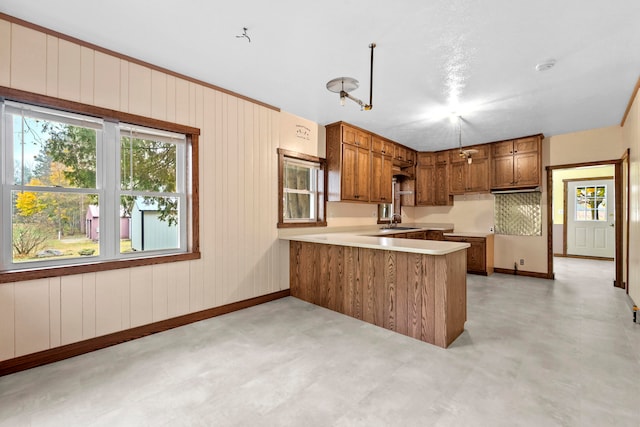 kitchen featuring kitchen peninsula, tasteful backsplash, sink, and wooden walls