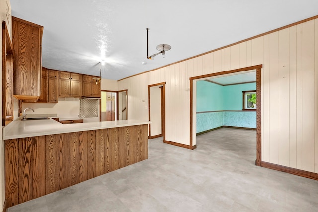 kitchen featuring wooden walls, tasteful backsplash, sink, and kitchen peninsula