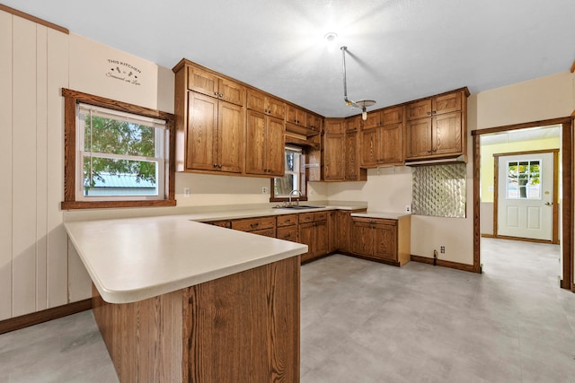 kitchen featuring sink, kitchen peninsula, backsplash, and plenty of natural light