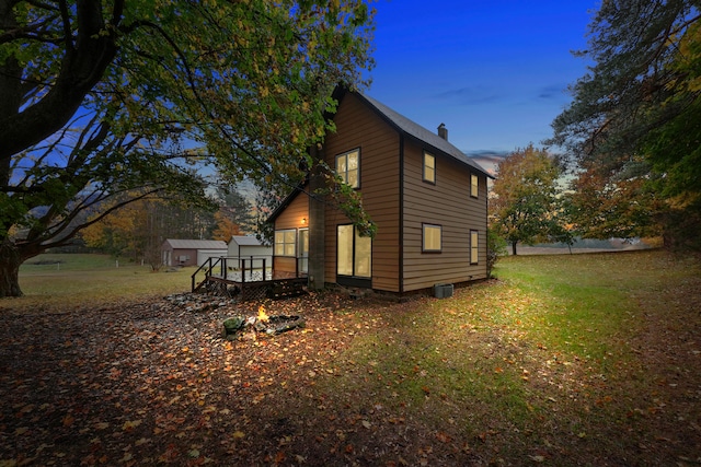 property exterior at dusk with a deck and a yard