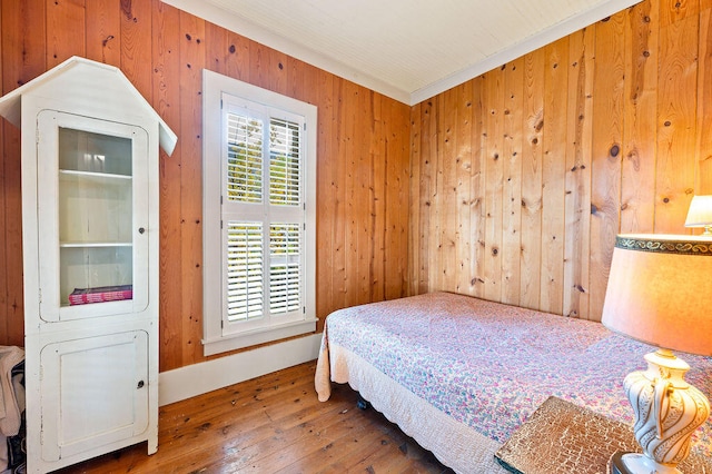 bedroom featuring dark wood-type flooring, crown molding, and wood walls