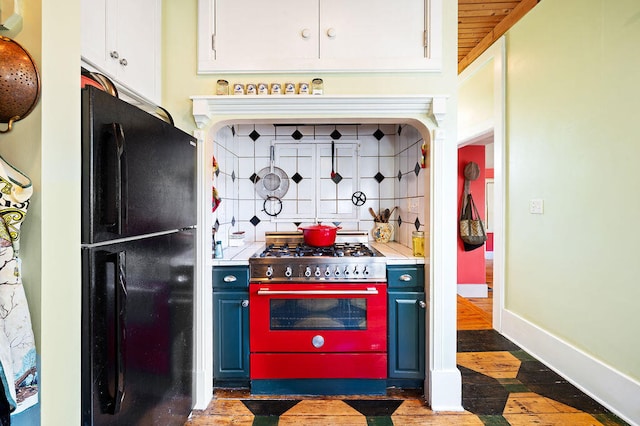 kitchen with backsplash, black fridge, white cabinetry, stainless steel range with gas cooktop, and wooden ceiling