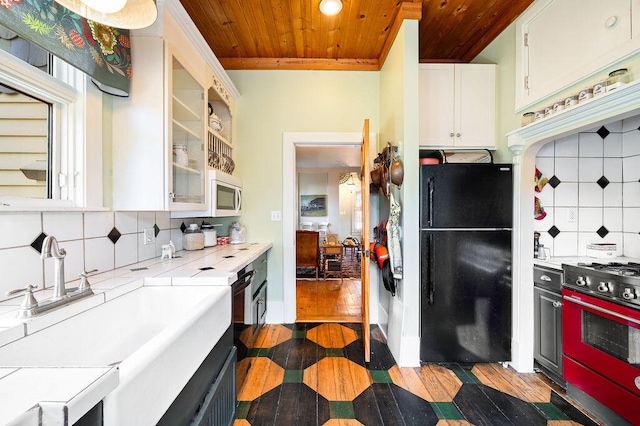 kitchen featuring white cabinets, tasteful backsplash, black refrigerator, and dark hardwood / wood-style flooring