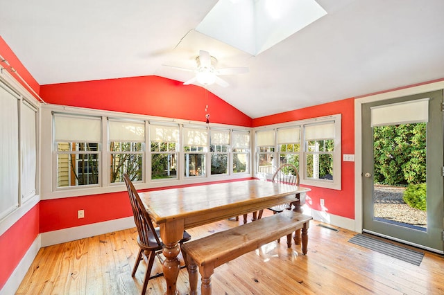 dining area with light hardwood / wood-style floors, lofted ceiling with skylight, and ceiling fan