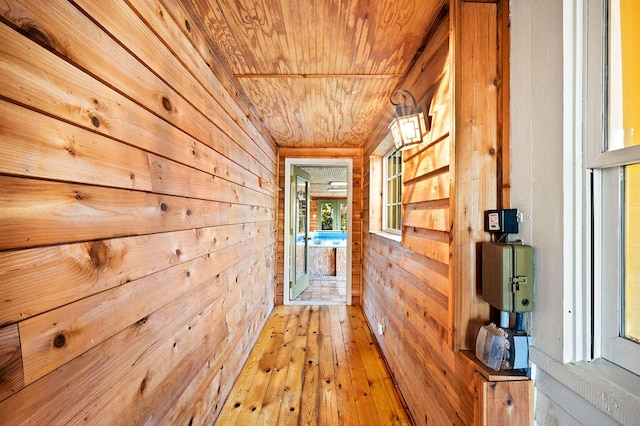 hall featuring wood ceiling, wood-type flooring, and wooden walls