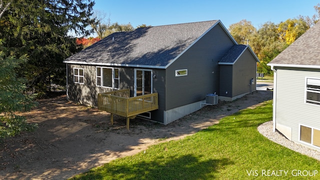 back of house with cooling unit, a deck, and a lawn