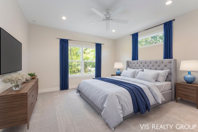 bedroom featuring light carpet, multiple windows, and ceiling fan