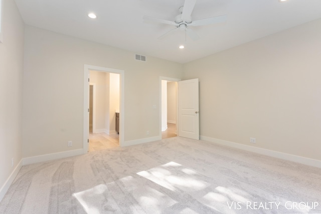 unfurnished bedroom featuring light carpet, ensuite bath, and ceiling fan