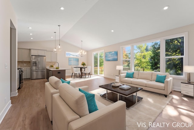 living room with sink, light hardwood / wood-style flooring, vaulted ceiling, and an inviting chandelier