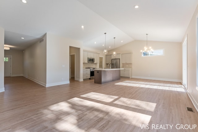 unfurnished living room featuring light hardwood / wood-style floors, vaulted ceiling, and a chandelier