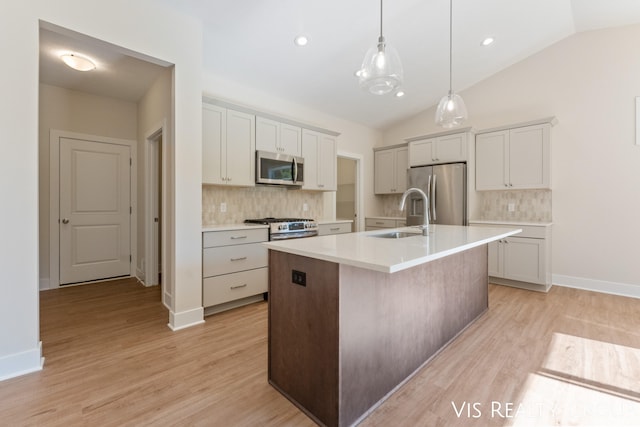 kitchen featuring sink, appliances with stainless steel finishes, lofted ceiling, and a kitchen island with sink