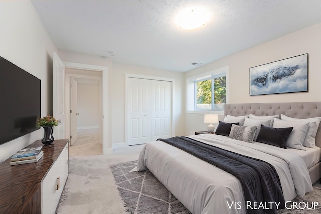 carpeted bedroom with a textured ceiling and a closet