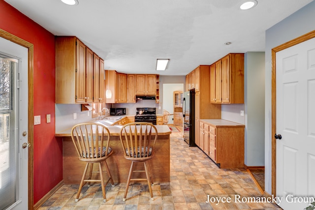 kitchen with black appliances, sink, kitchen peninsula, and a kitchen breakfast bar