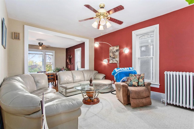 carpeted living room with radiator and ceiling fan