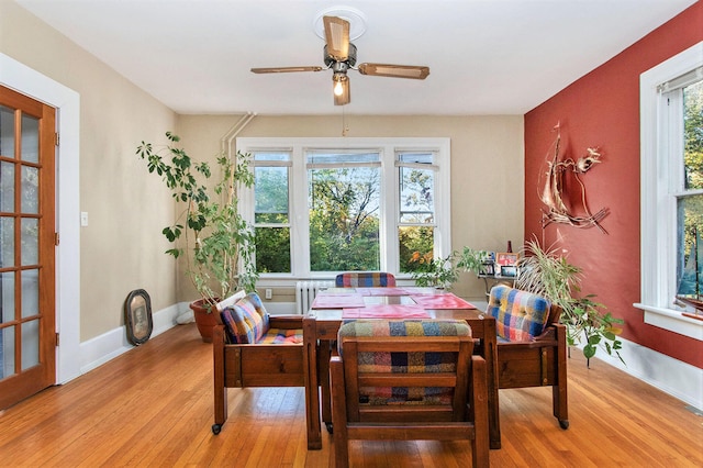 dining area with light wood-type flooring, ceiling fan, and radiator