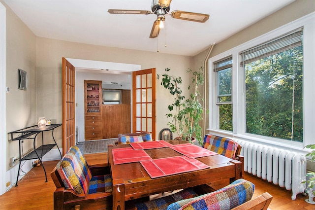 dining space featuring light hardwood / wood-style floors, ceiling fan, and radiator heating unit