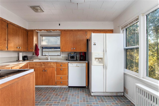 kitchen featuring radiator heating unit, sink, and white appliances