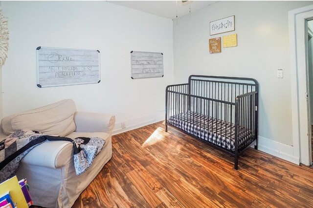 bedroom featuring hardwood / wood-style floors and a crib