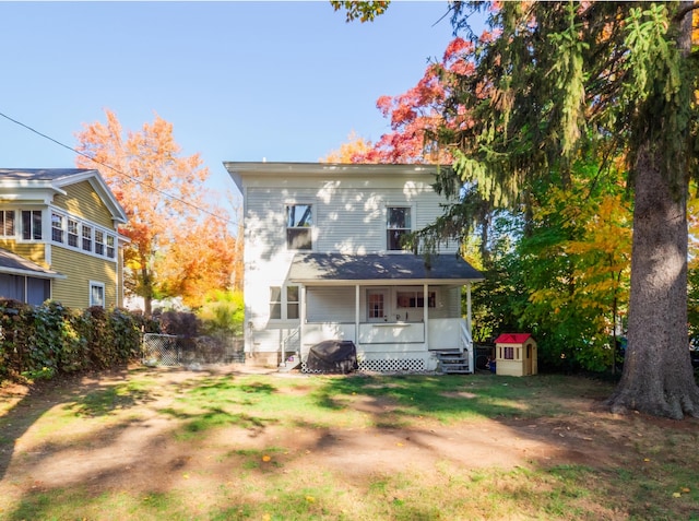 rear view of property with a storage shed and covered porch