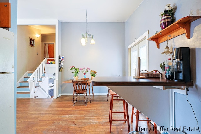 kitchen featuring white fridge, a notable chandelier, light hardwood / wood-style flooring, and hanging light fixtures