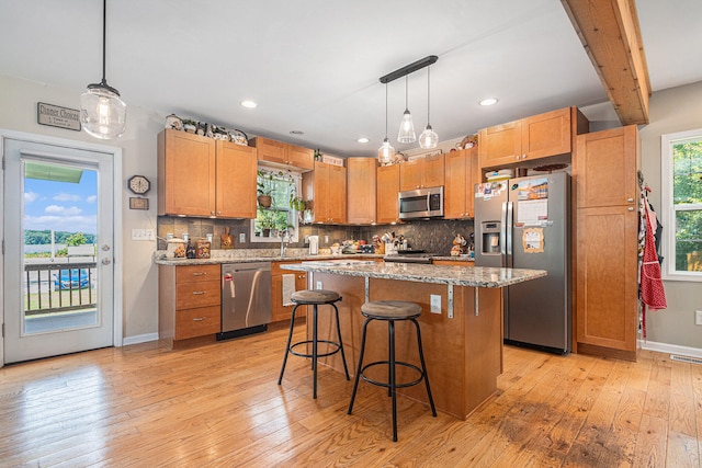 kitchen featuring light hardwood / wood-style floors, appliances with stainless steel finishes, a center island, and hanging light fixtures