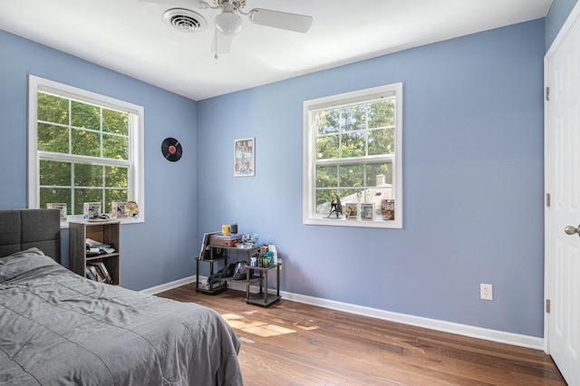 bedroom with hardwood / wood-style floors, multiple windows, and ceiling fan