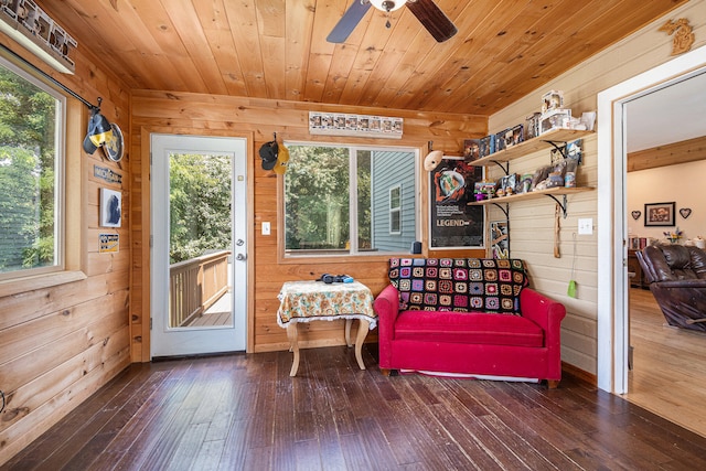 living area with wood ceiling, hardwood / wood-style flooring, wooden walls, and ceiling fan