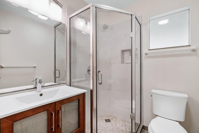 bathroom featuring vanity, a shower with shower door, and toilet